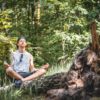 man meditating on a tree log