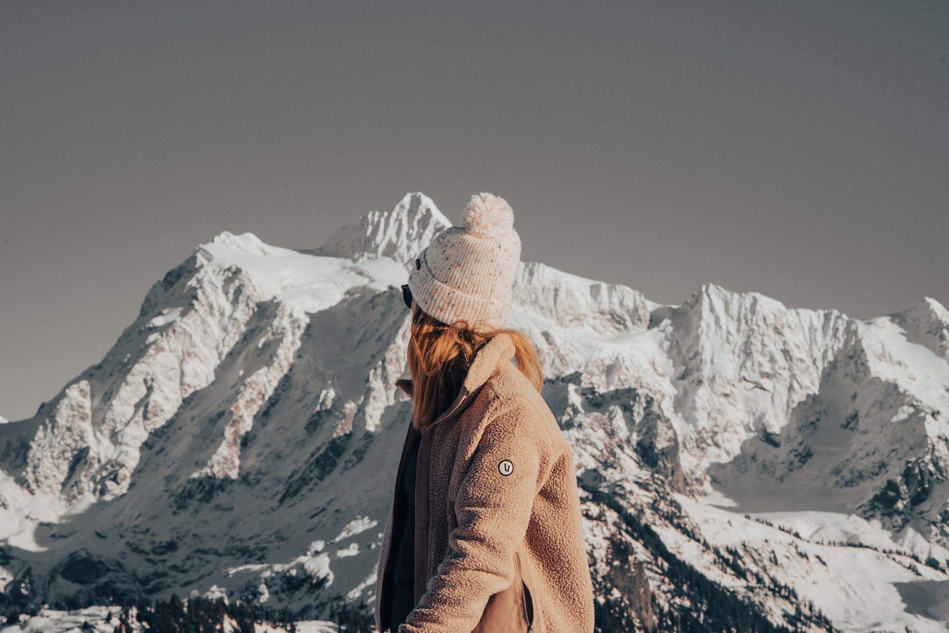 woman looking behind her at the snow covered steep mountains